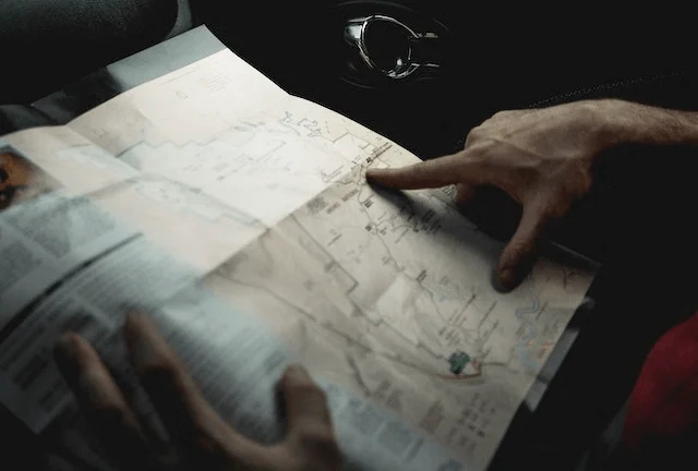 Person inside a black car checking a map, symbolizing planning the route and distance from Houston to Galveston.